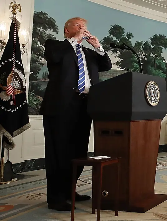 Presiden AS Donald Trump meminum air dari botol mineral disela menyampaikan pidatonya di Ruang Diplomatik, Gedung Putih, Rabu (15/11). Meski tak ada yang aneh, tapi sosial media langsung ramai bahkan media ikut memberitakan. (MARK WILSON/GETTY IMAGES/AFP)