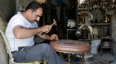 Ahmad Zuhdi Ghazoul menyelesaikan pekerjaannya di pasar tembaga yang baru direnovasi di Aleppo, Suriah, Minggu (28/7/2019 ). Kegiatan ekonomi perlahan mulai tumbuh tiga tahun setelah pertempuran besar terjadi di Aleppo. (AP Photo/Hassan Ammar)