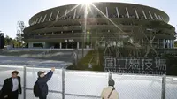 Orang-orang melihat Stadion Nasional Tokyo untuk Olimpiade dan Paralimpiade Tokyo 2020 setelah selesai direnovasi di Tokyo (30/11/2019). tadion berkapasitas 60 ribu itu akan menjadi venue upacara pembukaan serta berbagai nomor atletik dan cabang sepak bola. (Masanori Takei/Kyodo News via AP)