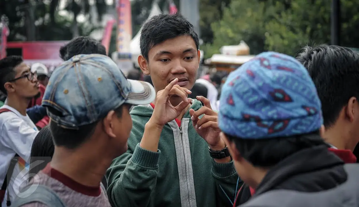 Seorang penyandang disabilitas tuna rungu memperagakan bahasa isyarat kepada warga di arena Car Free Day, Jakarta, Minggu (25/9). Sosialisasi bahasa isyarat itu sebagai salah satu kampanye memperingati Hari Tuli Internasional. (Liputan6.com/Faizal Fanani)