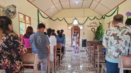 Puluhan jemaat tetap khidmat menyanyikan himne dalam misa Natal, ini menjadi ibadah pertama mereka sejak banjir dan tanah longsor. Tampak dalam foto, warga desa menghadiri Misa Natal di Gereja Protestan Angkola di desa Aek Ngadol, Tapanuli Selatan, Sumatera Utara, pada Kamis 25 Desember 2025, setelah banjir dan tanah longsor yang melanda di daerah tersebut pada akhir November 2025 lalu. (AMROE/AFP)