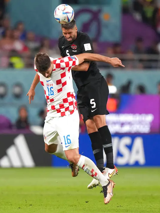 Pemain Kanada Steven Vitoria (5) menyundul bola melewati pemain Kroasia Bruno Petkovic (16) pada pertandingan sepak bola Grup F Piala Dunia 2022 di Stadion Internasional Khalifa, Al Rayyan, Qatar, 27 November 2022. Kroasia mengalahkan Kanada dengan skor 4-1. (Nathan Denette/The Canadian Press via AP)