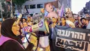 Seorang wanita berbicara melalui megafon ketika para aktivis Israel berbaris dengan membawa karung-karung tepung menuju markas besar Kementerian Pertahanan Israel di Tel Aviv pada 22 Juli 2025. (Jack GUEZ/AFP)