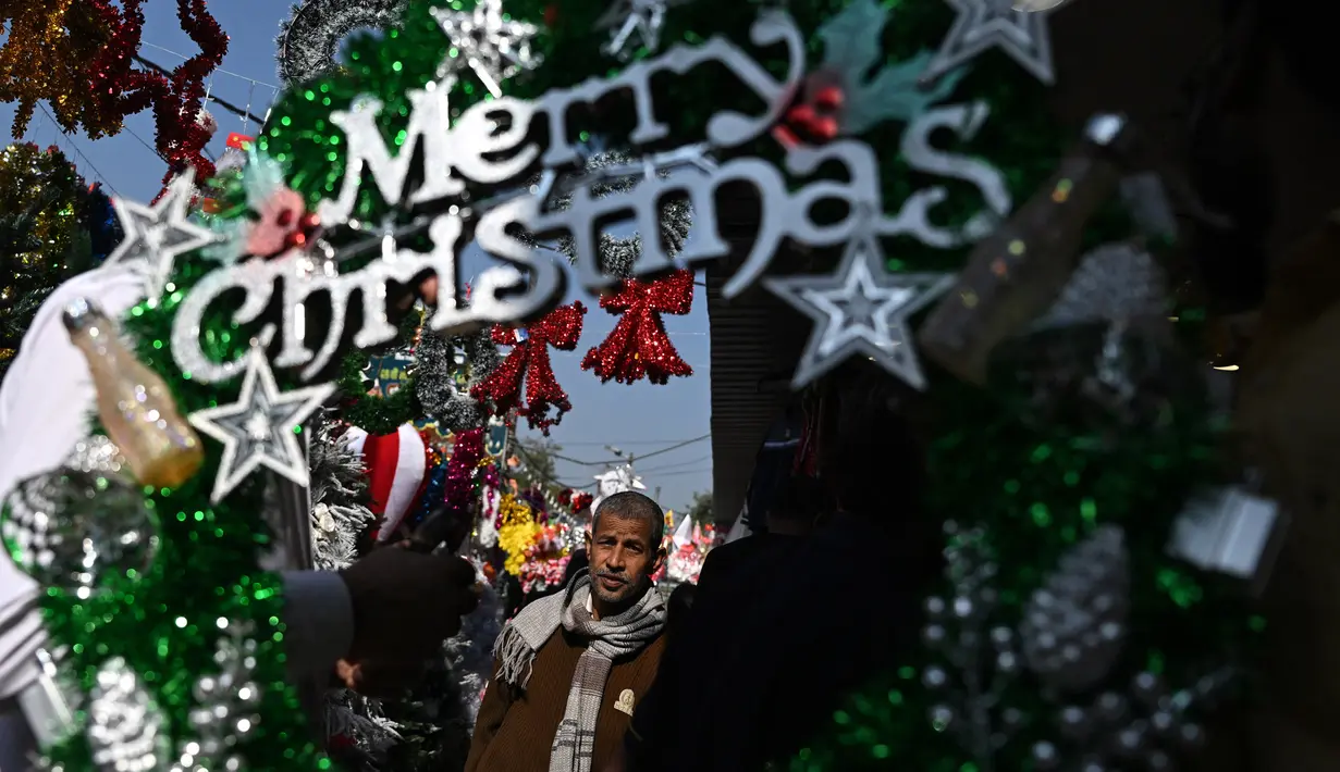 Seorang pria melintas di dekat barang-barang dekoratif yang dipajang di sebuah pasar menjelang perayaan Natal di New Delhi, India pada 13 Desember 2024. (Arun SANKAR/AFP)