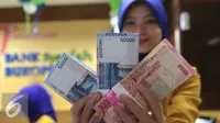 Petugas Bank memperlihatkan uang pecahan Rp100.000 dan Rp 50.000, Jakarta, Selasa (29/12). Di pasar spot, Senin (28/12), rupiah melemah tipis 0,08% ke Rp 13.642 per dollar AS. (Liputan6.com/Angga Yuniar)