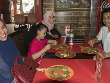 Pelatih Mitra Kukar, Jafri Sastra, didampingi istri dan kedua anaknya makan sate padang di kawasan Jakarta Selatan, Sabtu (23/1/2016). (Bola.cm/Vitalis Yogi Trisna)