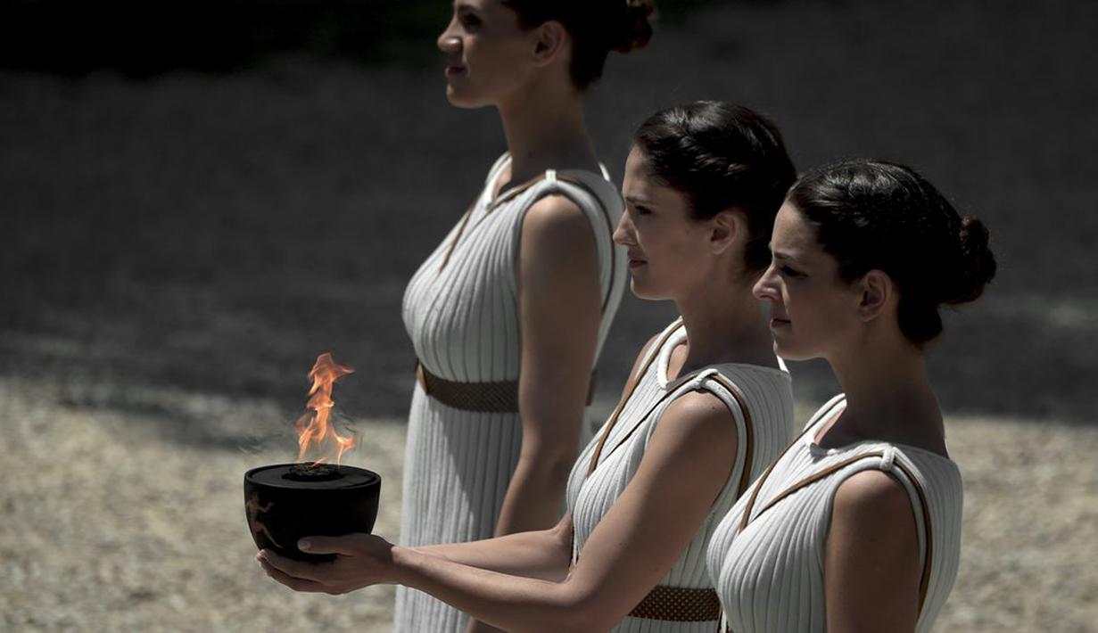 Para aktris Yunani, Katerina Lechou, membawa api olimpiade yang baru saja dinyalakan dalam suatu upacara di Candi Hera yang terletak di bekas kota tua Olympia, Yunani, Kamis (21/4/2016). (AFP/Aris Messinis)