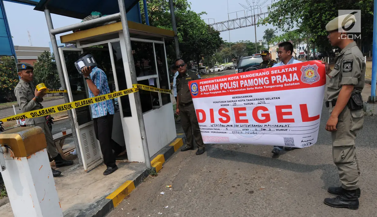 Petugas Satuan Polisi Pamong Praja (Satpol PP) Kota Tangerang Selatan memasang spanduk penyegelan areal parkir liar di kawasan BSD, Rabu (3/10). Penyegelan tersebut dilakukan lantaran pihak pengelola parkir tidak memiliki izin. (Merdeka.com/Arie Basuki)