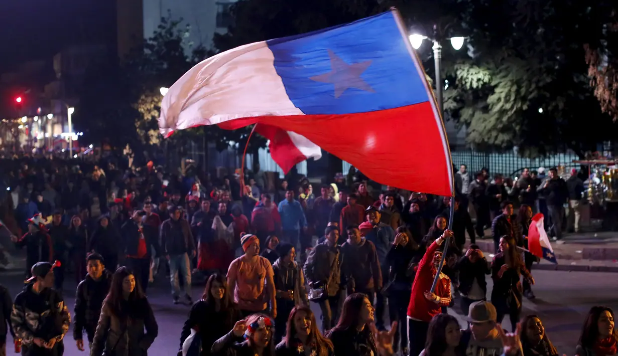 Seorang Suporter membawa bendera nasional Chile di kerumunan merayakan kemenangan Chile atas Uruguay di Copa America 2015 di Santiago, Chile, (25/6/2015). Chile melaju ke semifinal usai mengalahkan Uruguay 1-0. (REUTERS/Pablo Sanhueza)