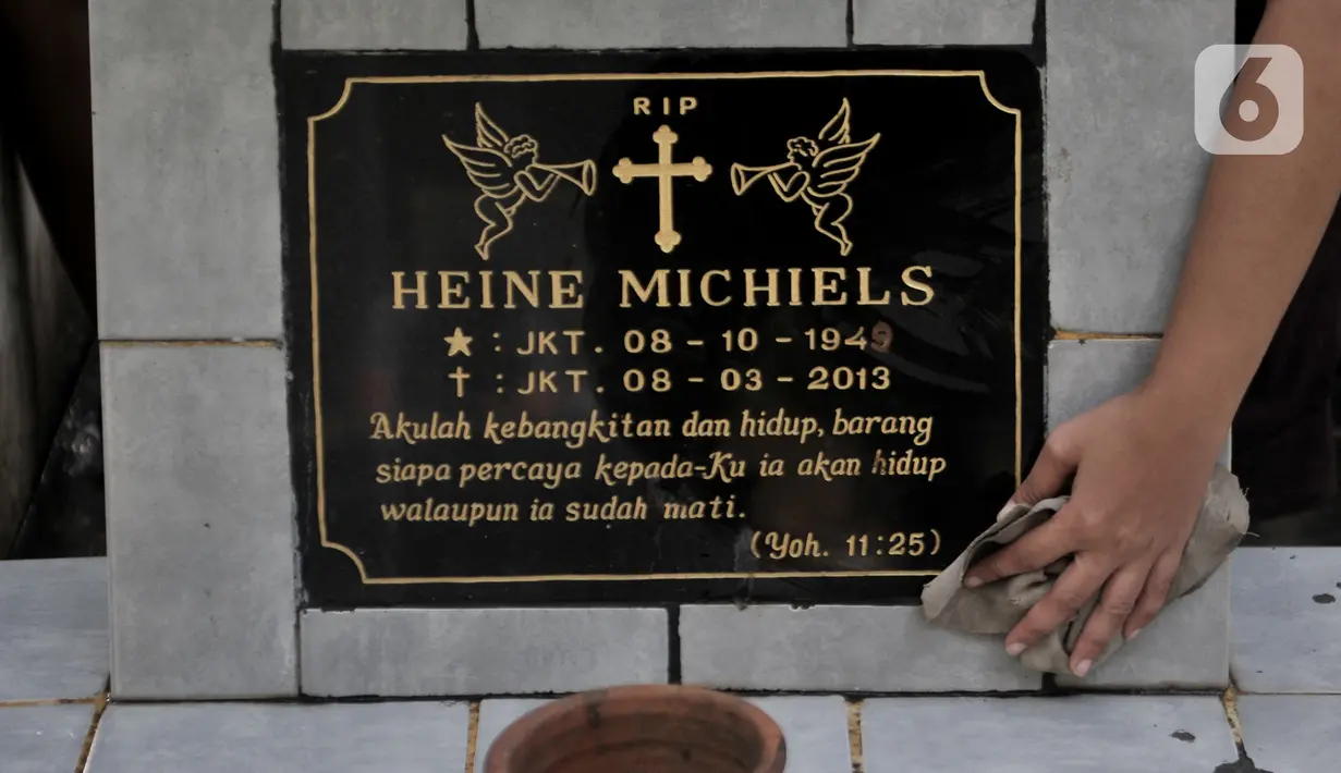 Keluarga membersihkan makam saat ziarah di kompleks pemakaman Gereja Tugu, Semper, Jakarta, Senin (23/12/2019). Warga keturunan Portugis melakukan ziarah ke makam keluarga mereka untuk merawat makam sekaligus mendoakan keluarga yang telah meninggal dunia. (merdeka.com/Iqbal Nugroho)