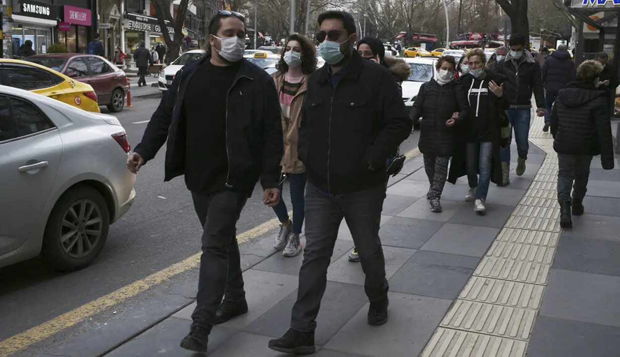 Orang-orang yang memakai masker untuk membantu melindungi dari penyebaran COVID-19 berjalan di Ankara, Turki, Senin (29/3/2021). Turki kembali memberlakukan lockdown akhir pekan dan pembatasan selama Ramadan menyusul peningkatan tajam kasus COVID-19. (AP Photo/Burhan Ozbilici)