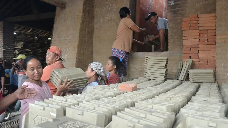 Pekerja perempuan memindahkan genteng setengah jadi di “tobong” atau tempat khusus pembakaran genteng soka. (Foto: Liputan6.com/Muhamad Ridlo)