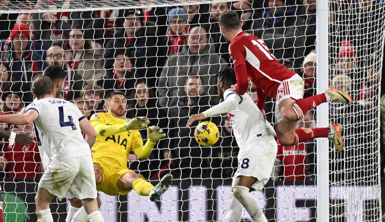 Kiper Tottenham Hotspur asal Italia, Guglielmo Vicario (dua kiri), berhasil menghalau bola sundulan dari pemain Nottingham Forest, Harry Toffolo (kanan), dalam pertandingan pekan ke-17 Liga Inggris 2023/2024 yang berlangsung di The City Ground, Sabtu (16/12/2023) dini hari WIB. (AFP/Oli Scarff)