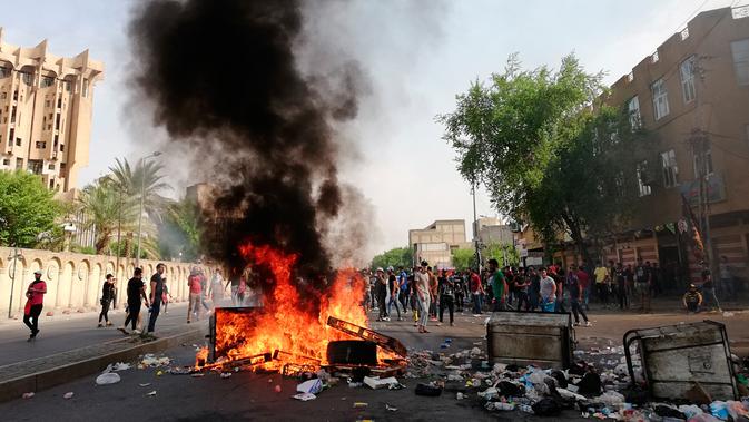 Pengunjuk rasa antipemerintah membakar sejumlah benda dan memblokir jalan saat menggelar protes di Baghdad, Irak, Rabu (2/10/2019). Ribuan demonstran berhadapan dengan tembakan dan gas air mata dalam unjuk rasa yang terjadi di sejumlah kota di Irak. (AP Photo/Hadi Mizban)