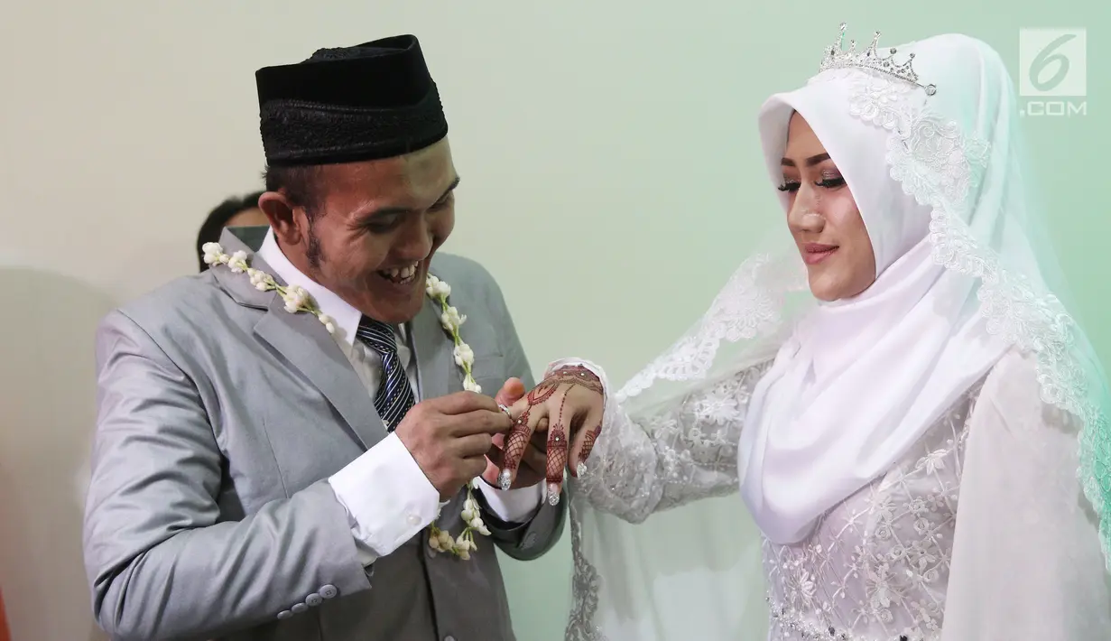 Komedian Caisar Aditya Putra memasangkan cincin ke jari Intan Sri Mardiani usai resmi menikah di kawasan Cimahpar, Bogor, Jawa Barat, Sabtu (30/6). Sama halnya dengan Caisar, Intan juga pernah menikah namun kandas. (Liputan6.com/Herman Zakharia)