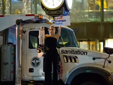 Penyanyi Lady Gaga berbusana serba hitam dan membawa bendera AS berunjuk rasa di depan Trump Tower, New York City, AS (9/11). Sebagai bentuk protesnya, Gaga mengangkat poster bertuliskan “Love Trumps Hate.”( AFP PHOTO / Dominick Reuter)