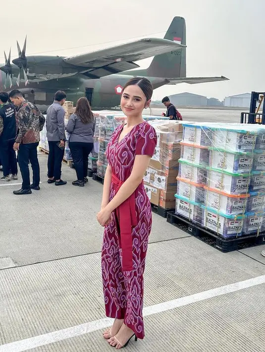 Syifa Hadju tampil menawan mengenakan jumpsuit pink dengan motif batik megamendung dipadukan kain merah yang diikat di perutnya. Lalu mengenakan heels strap transparan. [@syifahadju]