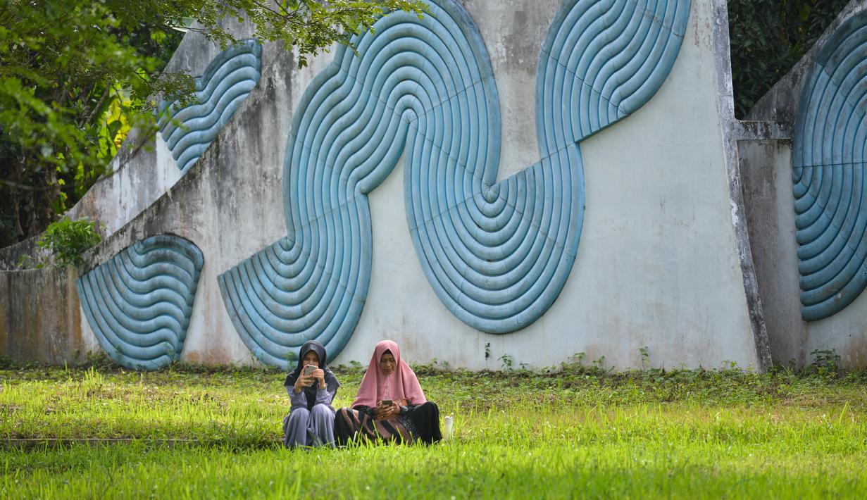 Seorang perempuan dan anaknya berdoa saat memperingati 18 tahun musibah gempa dan tsunami di kuburan massal Siron, Aceh, Senin (26/12/2022). Tsunami Aceh pada 2004 merenggut nyawa lebih dari 170.000 orang di Indonesia saja. (AFP/Chaideer Mahyuddin)