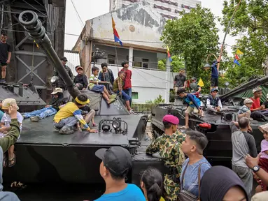 Orang-orang berfoto bersama kendaraan militer selama Pameran Marinir Indonesia, yang menandai peringatan Hari Ulang Tahun ke-80 Korps Marinir TNI AL di Surabaya, Jawa Timur pada Minggu 9 November 2025. Beberapa anak antusias menaiki kendaraan tempur milik Korps Marinir TNI AL yang dipamerkan di ruas jalan sekitar kawasan Gedung Negara Grahadi, Surabaya, Jawa Timur. (JUNI KRISWANTO/AFP)