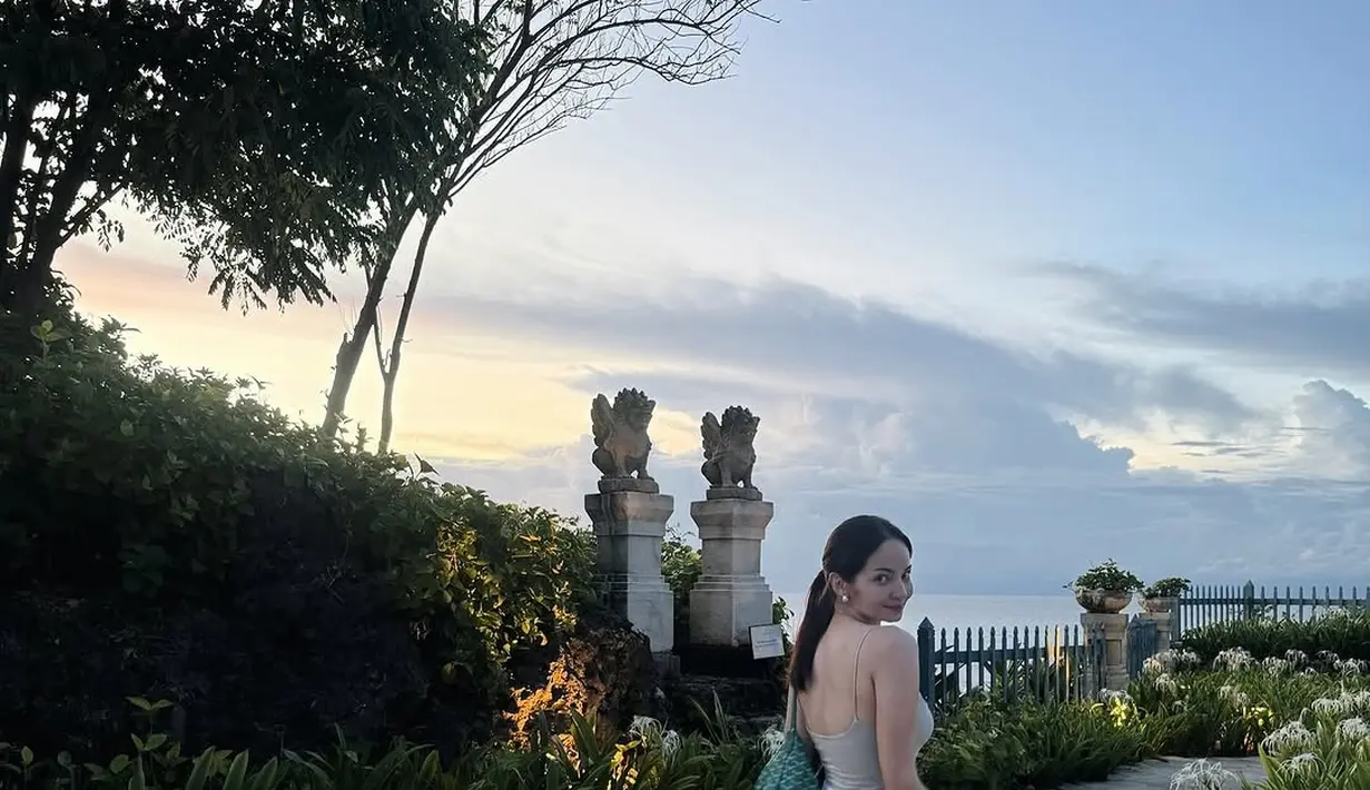 Masih dengan nuansa kasual, Enzy memilih tank top warna cream, dipadukan dengan short pants putih, serta sandal slip-on warna putih. Namun yang membuat penampilan ini standout adalah tas Goyard warna hijau yang mencuri perhatian dan memberi statement tersendiri. Penampilannya pun makin lengkap dengan sentuhan anting-anting silver yang simpel namun elegan.  [@enzystoria].