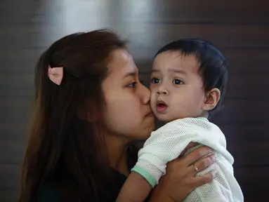 Sambil mencium anaknya, Enry Khairul terus menunggu kabar suaminya, Mohd Khairul Amri Selamat yang menjadi penumpang Malaysia Airlines MH370 (REUTERS/Samsul Said)