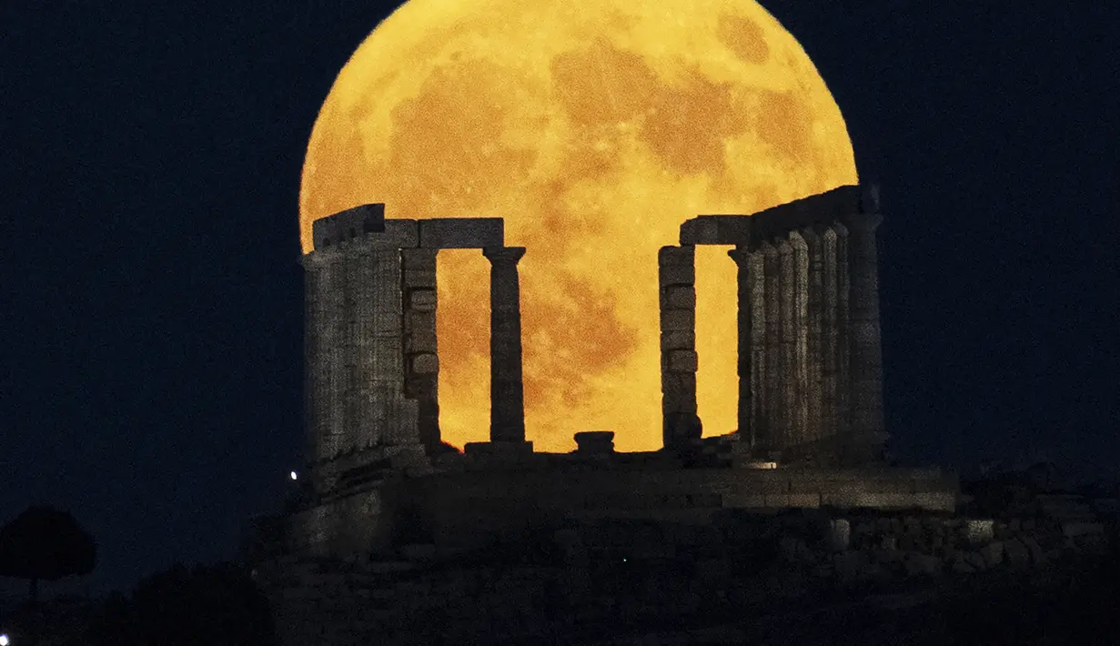 Bulan purnama terbesar atau supermoon muncul di belakang Kuil Poseidon di Tanjung Sounio, selatan Athena, Senin (19/8/2024). (AP Photo/Michael Varaklas)