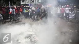 Petugas memadamkan atribut yang dibakar oleh massa saat aksi berlangsungnya unjuk rasa memperingati hari Nelayan Nasional didepan Istana Merdeka, Jakarta, Rabu (6/4). (Liputan6.com/Faizal Fanani)
