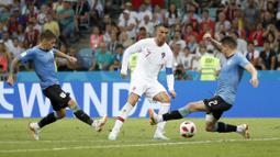 Cristiano Ronaldo berusaha melewati adangan dua pemain Uruguay pada laga 16 besar Piala Dunia 2018 di Fisht Stadium, Sochi, Rusia, (30/6/2018). Portugal kalah 1-2 dari Uruguay. (AP/Francisco Seco)