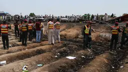Petugas penyelamat Pakistan mengevakuasi lokasi ledakan truk tangki minyak di jalan raya dekat Bahawalpur, Pakistan (25/6). Korban tewas mayoritas mereka yang awalnya mencoba mengumpulkan bahan bakar yang tercecer dari truk tangki. (AP Photo / Iram Asim)