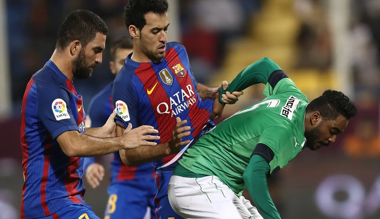 Pemain Barcelona, Arda Turan dan Sergio Busquets, berebut bola dengan pemain Al Ahli, Ali al-Zubaidi, pada laga persahabatan di Stadion Thani bin Jassim, Doha, Selasa (13/12/2016) waktu setempat. (AFP/Karim Jaafar)