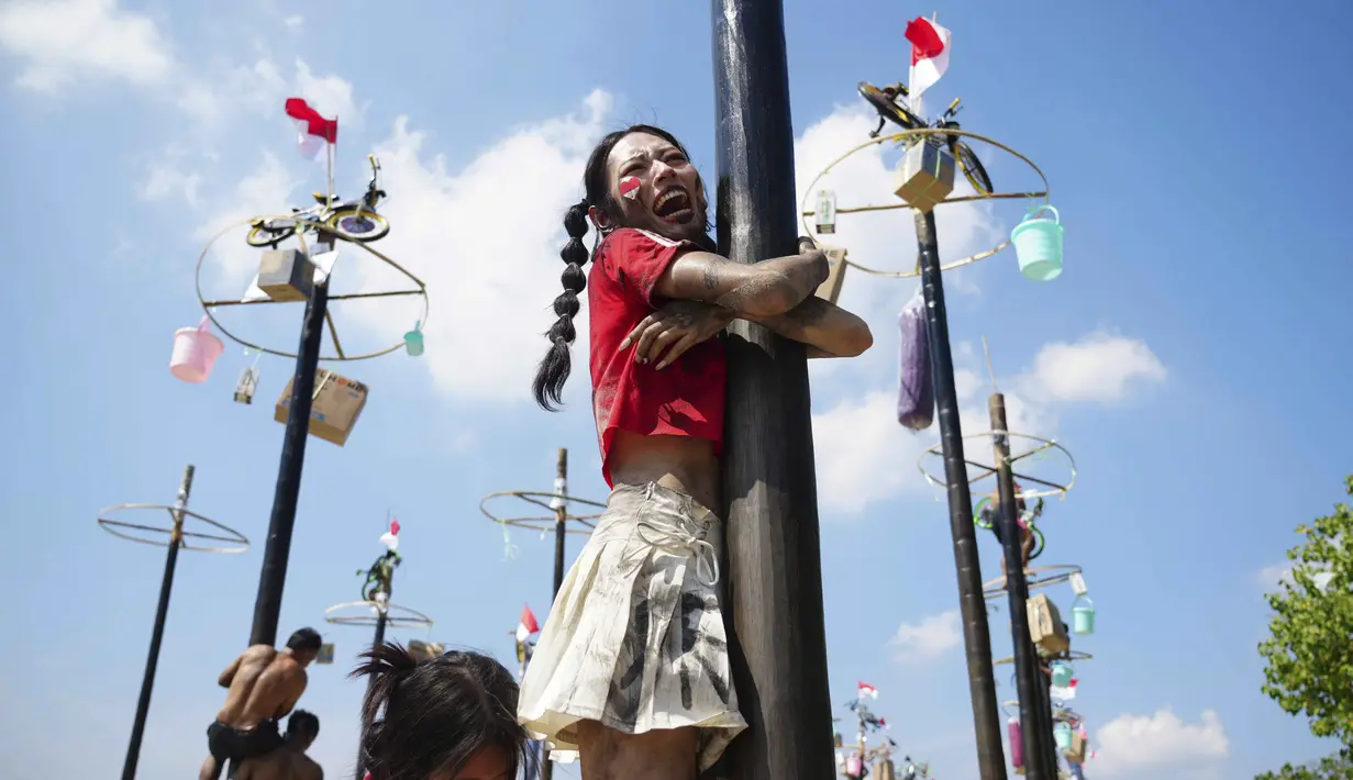 Salah satu wisatawan asing terlihat antusias mengikuti lomba panjat pinang kolosal yang diadakan untuk merayakan HUT ke-80 Kemerdekaan Indonesia, di Pantai Ancol, Jakarta, Minggu 17 Agustus 2025. (AP Photo/Tatan Syuflana)