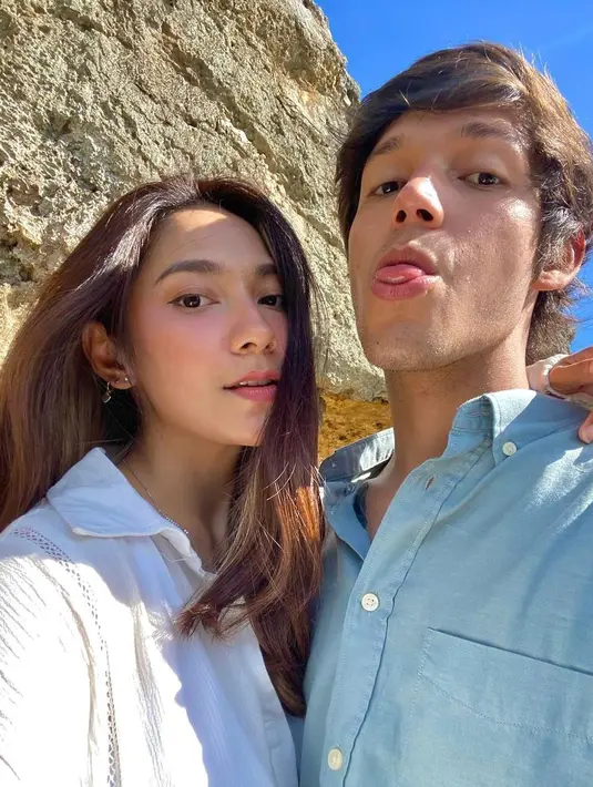 Saat foto bareng, kemeja warna biru dan putih menjadi kombinasi yang indah dengan latar langit biru cerah dan batu karang. (Foto: Instagram @dindakirana.s)