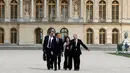 Presiden Prancis Emmanuel Macron dan Presiden Rusia, Vladimir Putin didampingi juru bicara masing-masing menuju taman Istana Versailles, dekat Paris, setelah mereke menggelar pertemuan, Senin (29/5). (AP Photo/Francois Mori, pool)
