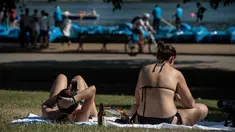 Dua wanita saat berjemur saat suhu musim panas mencapai sekitar 28 derajat di dekat Serpentine di Hyde Park di London, Inggris (5/7). (AFP Photo/Chris J Ratcliffe)