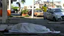 Seorang pria melihat ke arah jenazah yang tergeletak selama tiga hari di luar sebuah klinik di Guayaquil, Ekuador, Jumat (3/4/2020). Di Guayaquil, banyak dijumpai jenazah korban virus corona COVID-19 yang terlantar di jalanan. (Str/Marcos Pin/AFP)