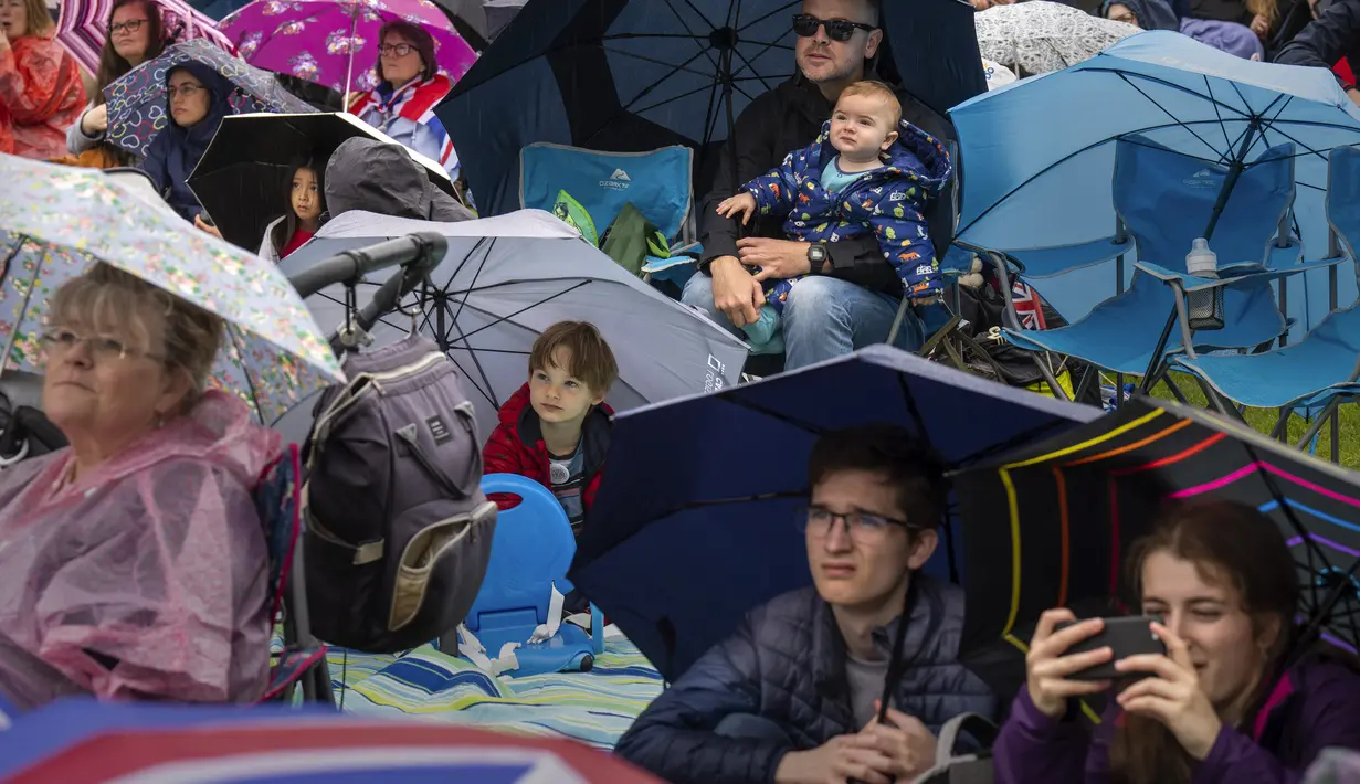Para penggemar kerajaan Inggris menonton upacara penobatan Raja Charles III dari layar di taman Hyde,  London, Sabtu (6/5/2023). (AP Photo/Emilio Morenatti)