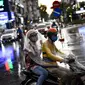 Seorang penumpang berlindung di bawah kantong plastik dengan pengemudi ojek saat hujan di Hanoi, ibu kota Vietnam pada 11 Agustus 2020. Setelah mencatat nol kasus COVID-19 selama lebih dari tiga bulan, Vietnam melaporkan sejumlah infeksi baru di dalam negeri sejak akhir Juli. (MANAN VATSYAYANA/AFP)