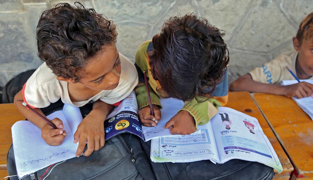 Anak-anak Yaman menghadiri kelas di luar ruangan sebuah sekolah yang rusak parah pada hari pertama tahun ajaran baru di provinsi barat Yaman yang dilanda perang Hodeida, Senin (17/10/2022). UNICEF memperkirakan bahwa lebih dari dua juta anak telah putus sekolah di Yaman, peningkatan hampir setengah juta sejak perang pecah pada 2015. (Foto oleh Khaled ZIAD / AFP).