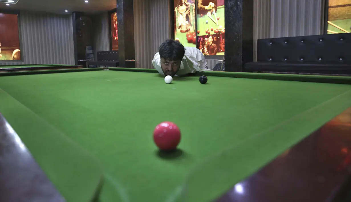 Mohammad Ikram bermain snooker dengan dagunya di sebuah klub snooker lokal di kota Samundri, Pakistan, Minggu (25/10/2020). Dia tinggal di kota pedesaan terpencil di provinsi Punjab dan kecacatan fisiknya tidak menghalangi impian masa kecilnya untuk bermain snooker. (AP Photo/Anjum Naveed)