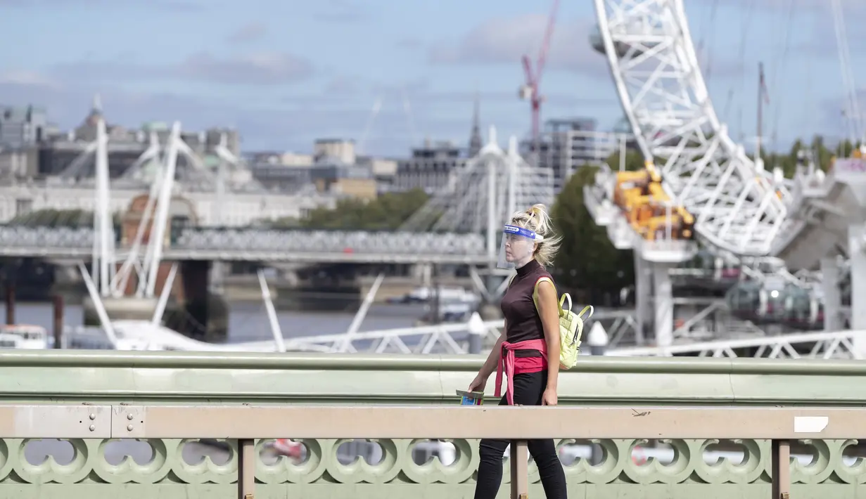 Seorang wanita yang mengenakan pelindung wajah berjalan melewati London Eye di London, Inggris (8/9/2020). Angka resmi terbaru Inggris pada Selasa (8/9) menunjukkan bahwa korban meninggal akibat COVID-19 di negara tersebut telah mencapai 57.400. (Xinhua/Han Yan)