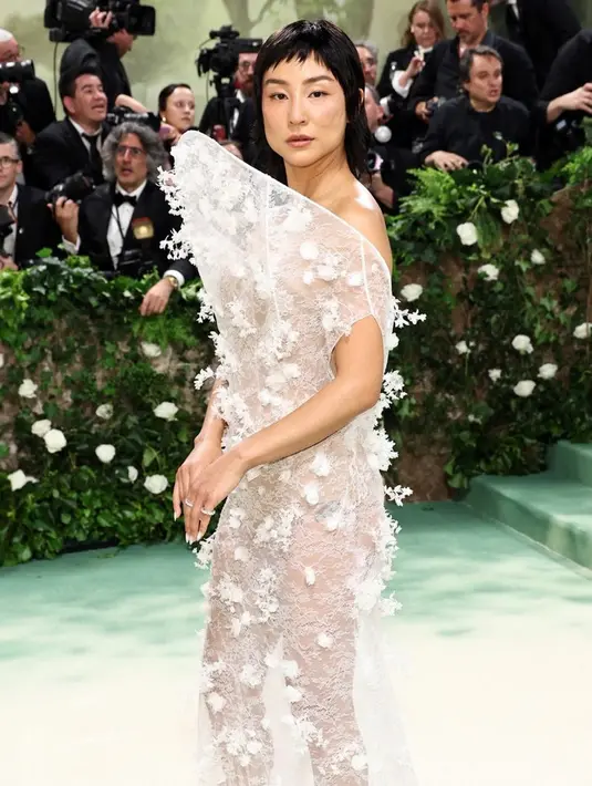 Greta Lee mengenakan gaun putih Loewe dengan hiasan bunga. Gaun tersebut tampak transparan. [@loewe]
