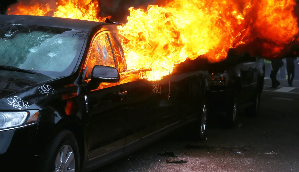 Kondisi Mobil limusin yang dibakar pengunjuk rasa selama protes pelantikan Presiden Donald Trump di Washington, DC, AS, (20/1). Mobil mewah tersebut menjadi bulan-bulanan massa anti-Trump. (Mario Tama/Getty Images/AFP)