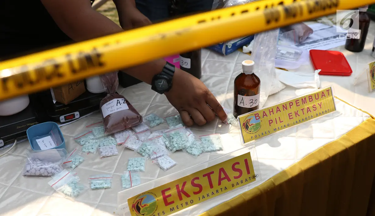 Petugas menunjukkan barang bukti pil ekstasi saat rilis di sebuah perumahan di Pondok Rajeg, Cibinong, Senin (24/9). Polisi menyita sejumlah barang bukti diantaranya 158 gram sabu, 3000 pil ekstasi dan satu paket ganja. (Liputan6.com/Helmi Fithriansyah)