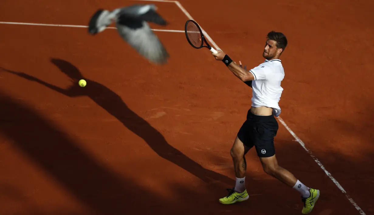 Seekor burung terbang melintasi lapangan tenis saat Martin Klizan melawan Gael Monfils pada ajang Prancis Terbuka 2018 di Roland Garros stadium, Paris, France, (30/5/2018). (AP/Christophe Ena)
