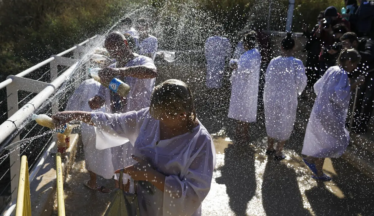Para peziarah Kristen Ortodoks mengumpulkan air dari Sungai Yordan saat upacara pembaptisan pada perayaan Epiphany di Qasr el Yahud, dekat kota Yerikho, Tepi Barat, 18 Januari 2022. Sungai Yordan dipercaya menjadi tempat di mana Yesus dibaptis. (AP Photo/Mahmoud Illean)
