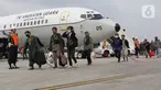 Tiga Warga Negara Indonesia (WNI) yang dipulangkan dari Sudan berjalan setibanya di Pangkalan Udara Halim Perdanakusuma, Jakarta, Senin (1/5/2023). Sebanyak 75 WNI tiba di tanah air dari Sudan dengan menggunakan pesawat TNI AU. (Liputan6.com/Helmi Fithriansyah)