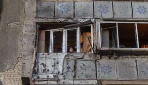 Seorang wanita berdiri di balkon sebuah bangunan tempat tinggal yang rusak akibat serangan, di Odesa, pada 31 Desember 2025, di tengah invasi Rusia di Ukraina. Jelang pergantian tahun, Rusia kembali melancarkan serangan drone yang menyasar wilayah Odesa, Ukraina, Selasa (30/12/2025) malam waktu setempat. (Oleksandr GIMANOV/AFP)