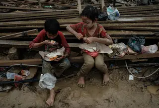 Anak-anak memakan makanan yang dibagikan di Babo, Aceh Tamiang, pada Senin 15 Desember 2025. Ancaman gangguan kesehatan menghantui anak-anak korban bencana banjir bandang dan tanah longsor yang terjadi di berbagai wilayah di Aceh, Sumatera Utara, dan Sumatera Barat. (Yasuyoshi CHIBA/AFP)