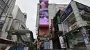 Seorang perempuan melewati layar listrik besar bergambar personel boyband BTS, Jeon Jung-kook, di sebuah distrik perbelanjaan di Seoul, Selasa (1/9/2020). Bangtan Boys (BTS) menjadi artis Korea Selatan pertama yang berhasil menempati puncak Billboard Hot 100 dengan lagu Dynamite. (Jung Yeon-je/AFP)