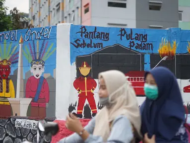 Pengendara motor melintas di depan mural bertema Kota Jakarta di sekitar Rusunawa KS Tubun, Jakarta, Senin (23/11/2020). Mural tersebut dibuat guna memercantik lingkungan di sekitar rusun agar lebih berwarna dan tidak tampak kumuh. (Liputan6.com/Immanuel Antonius)